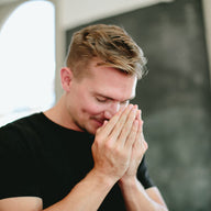 A man doing a saje breath, where his hands are tented by his nose