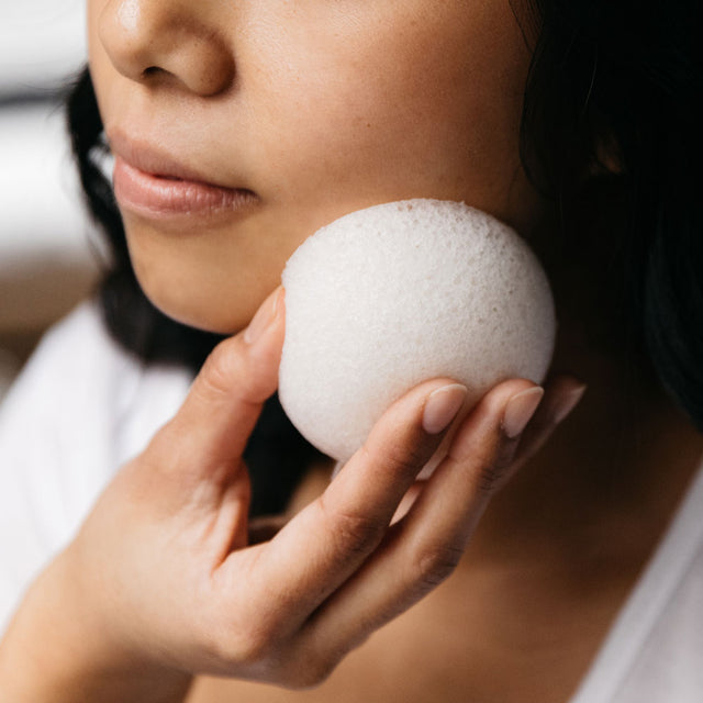 A person lightly exfoliating their skin with the Konjac Kare yam extract hydrating vegetable fibre sponge 